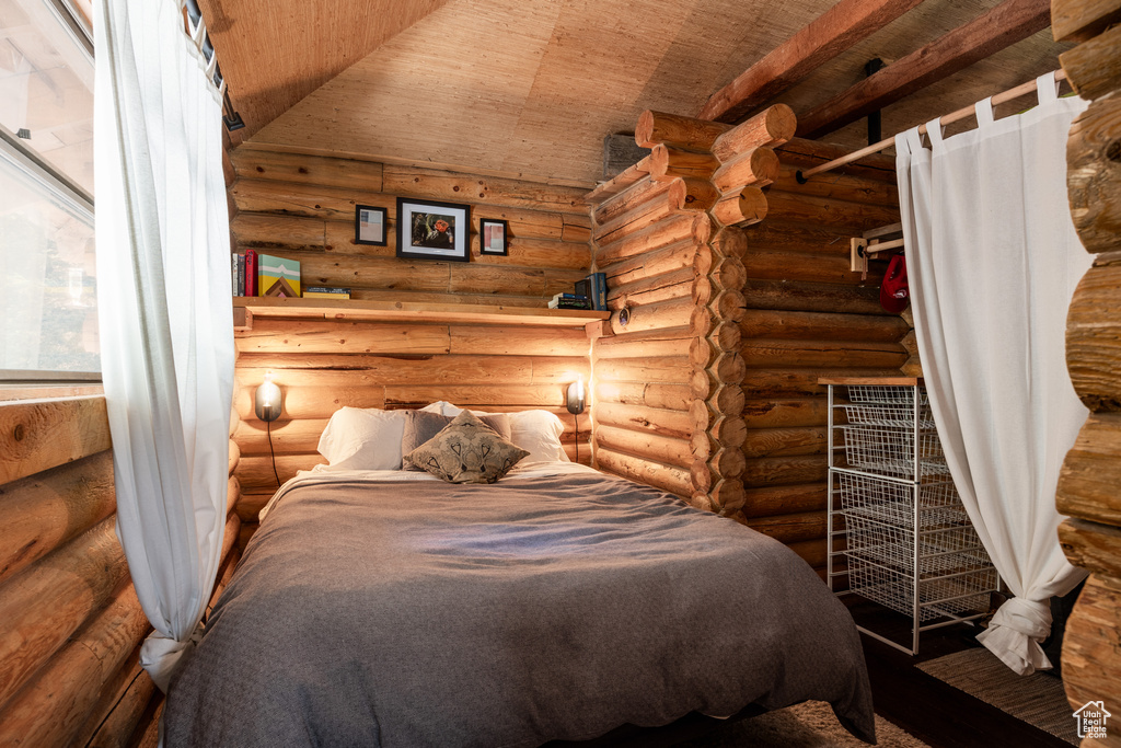 Bedroom featuring lofted ceiling, wooden ceiling, and rustic walls