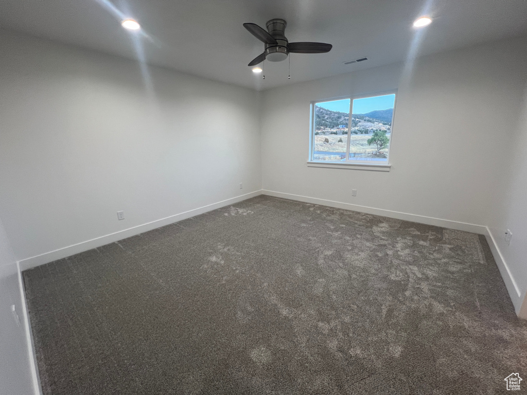 Carpeted spare room featuring ceiling fan