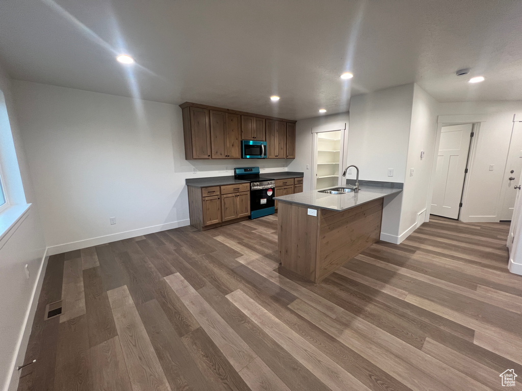 Kitchen with kitchen peninsula, electric stove, dark hardwood / wood-style floors, a kitchen breakfast bar, and sink