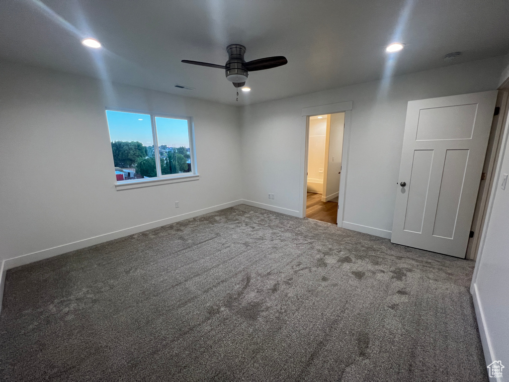 Unfurnished bedroom with ensuite bathroom, ceiling fan, and carpet flooring