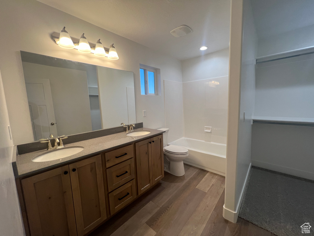 Full bathroom with double vanity, shower / bath combination, toilet, and hardwood / wood-style floors