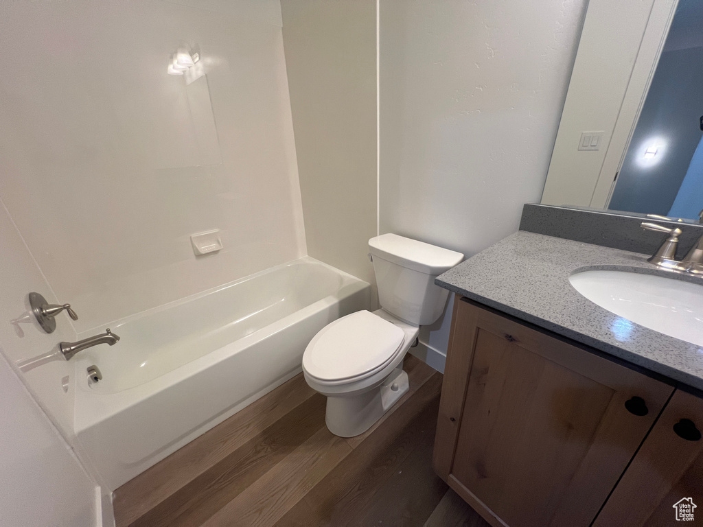 Full bathroom with hardwood / wood-style flooring, shower / bath combination, toilet, and vanity