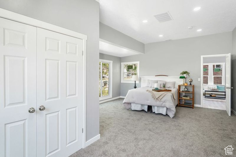 Carpeted bedroom with multiple windows and a closet