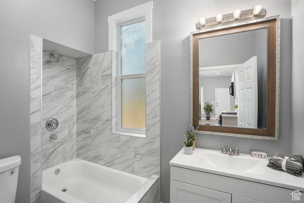 Full bathroom with vanity, tiled shower / bath combo, and toilet