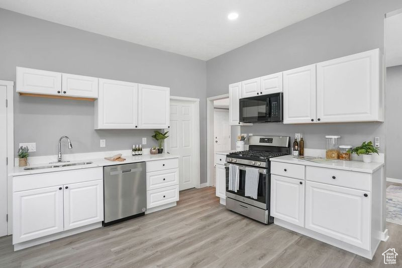 Kitchen featuring white cabinets, stainless steel appliances, light hardwood / wood-style floors, and sink