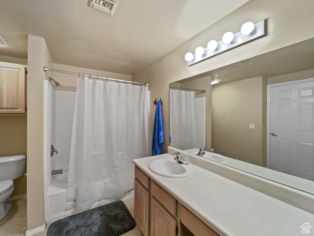 Full bathroom with vanity, toilet, tile patterned floors, and shower / bath combo