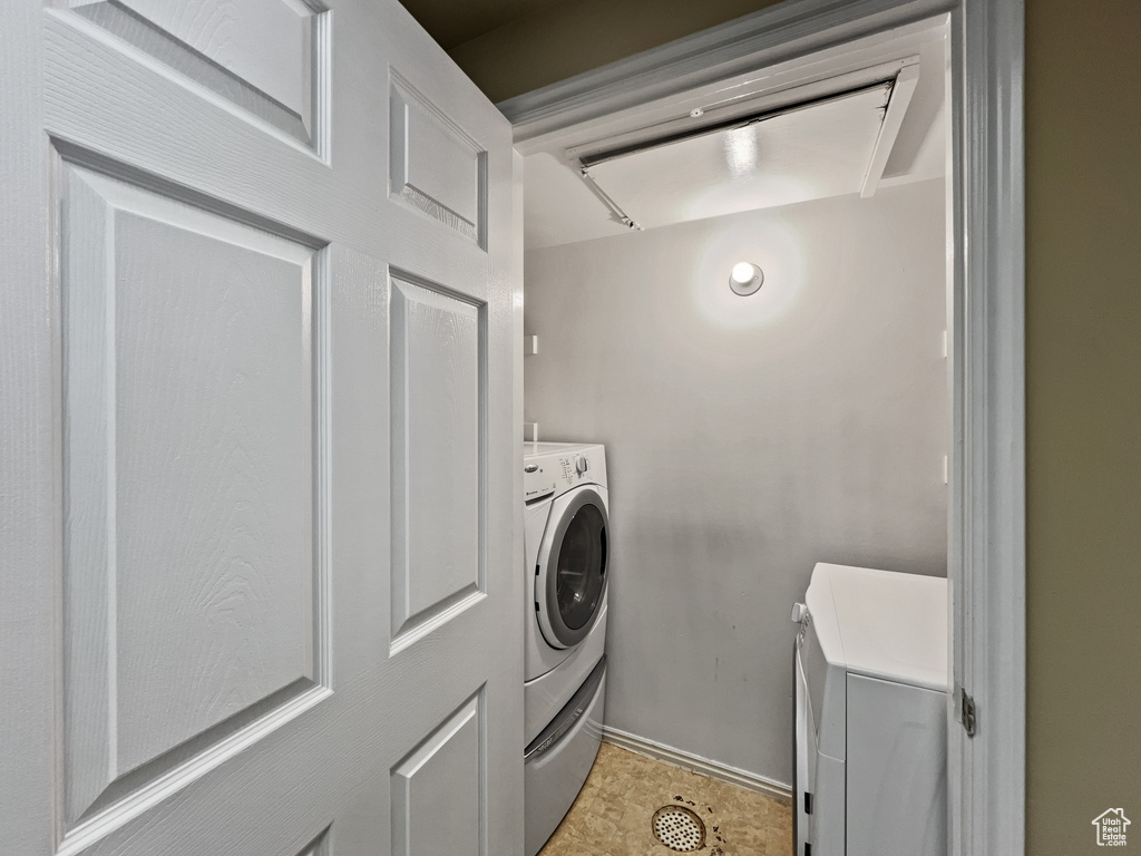 Washroom featuring light tile patterned flooring and washer and dryer