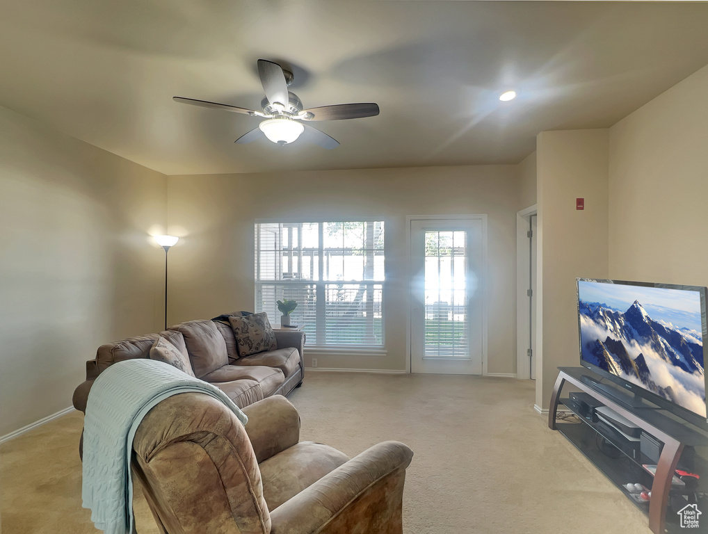 Living room featuring light carpet, a ceiling fan, and baseboards