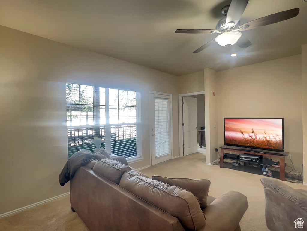 Living area with light carpet, a ceiling fan, and baseboards