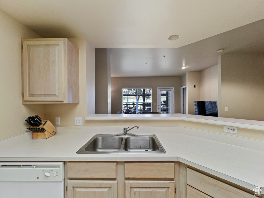 Kitchen featuring dishwasher, light brown cabinets, sink, and kitchen peninsula