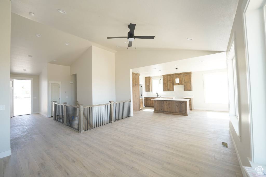 Interior space featuring light wood-type flooring, sink, ceiling fan, and high vaulted ceiling