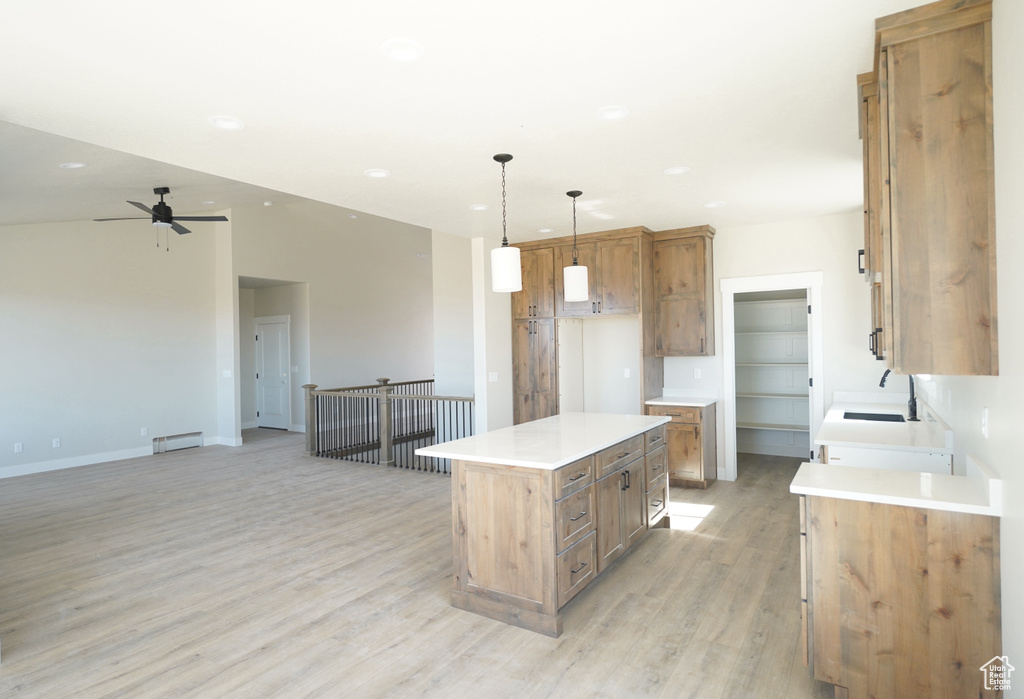 Kitchen featuring ceiling fan, sink, a kitchen island, light hardwood / wood-style flooring, and decorative light fixtures