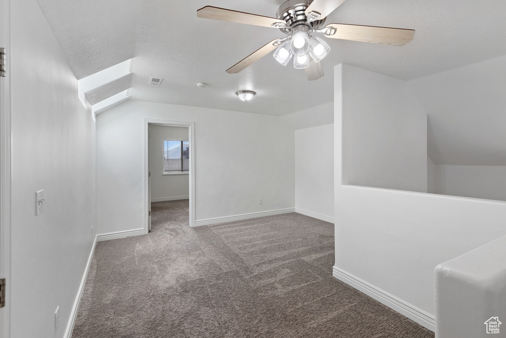 Additional living space featuring carpet, ceiling fan, and vaulted ceiling