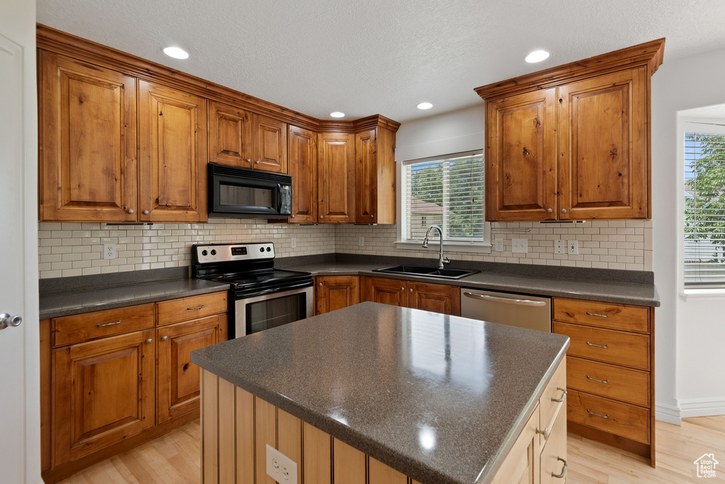 Kitchen featuring decorative backsplash, sink, appliances with stainless steel finishes, and light wood-type flooring