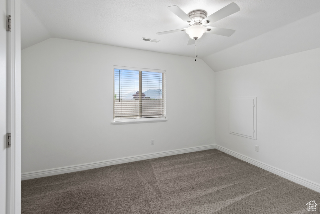 Carpeted empty room with ceiling fan and vaulted ceiling