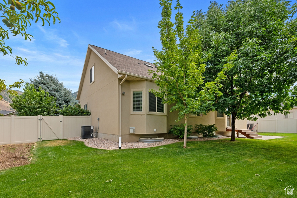 Back of house with central AC and a yard