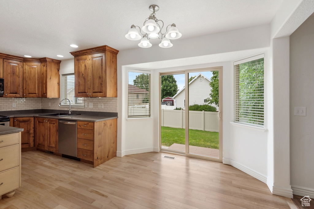 Kitchen with sink, stainless steel dishwasher, plenty of natural light, and light wood-type flooring