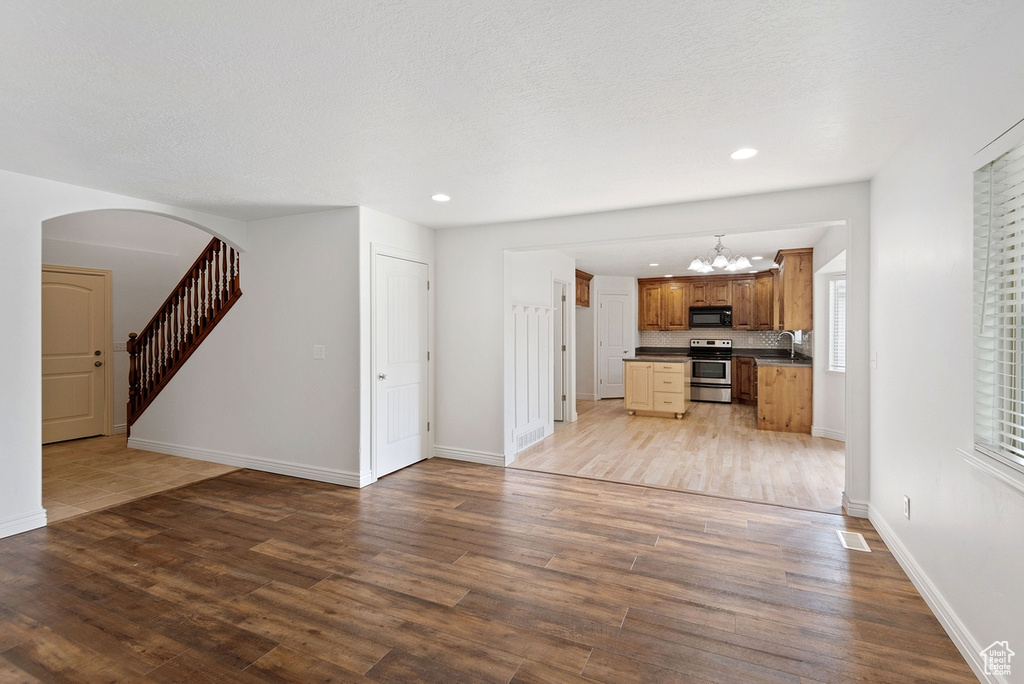 Unfurnished living room with wood-type flooring and a chandelier