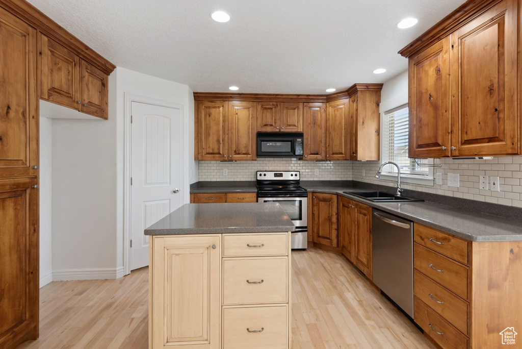 Kitchen featuring decorative backsplash, sink, a center island, appliances with stainless steel finishes, and light hardwood / wood-style flooring