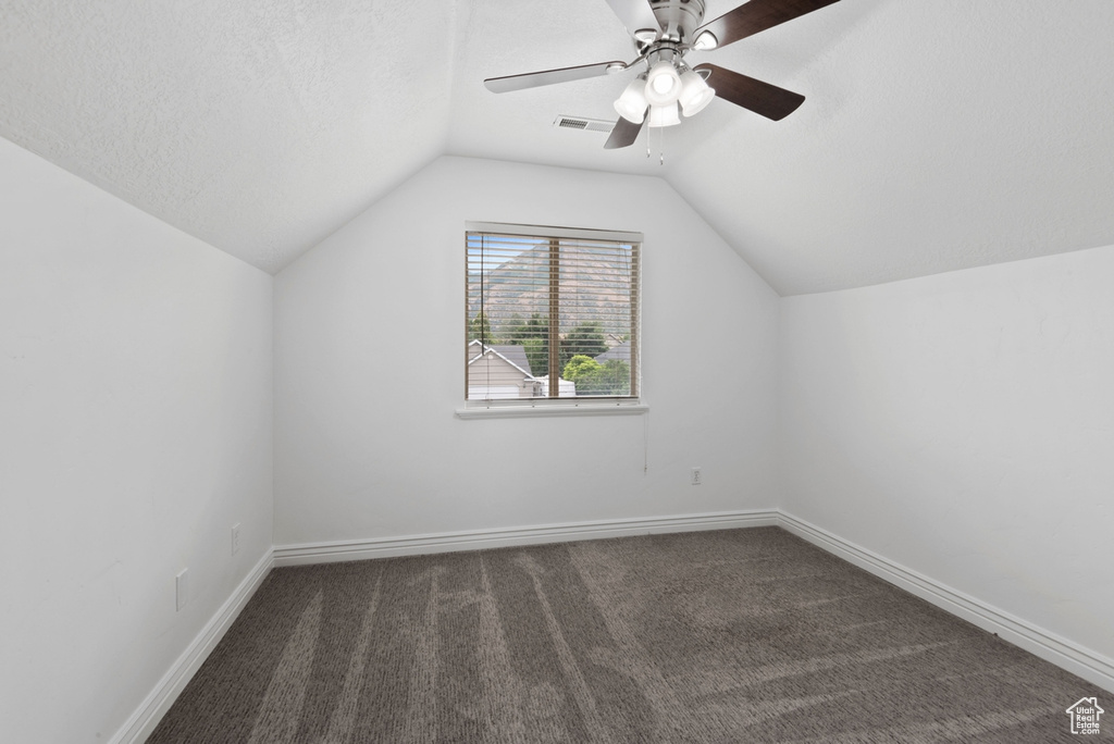 Additional living space with carpet flooring, a textured ceiling, ceiling fan, and vaulted ceiling