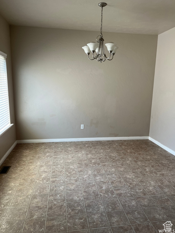 Unfurnished room with tile patterned floors and a chandelier