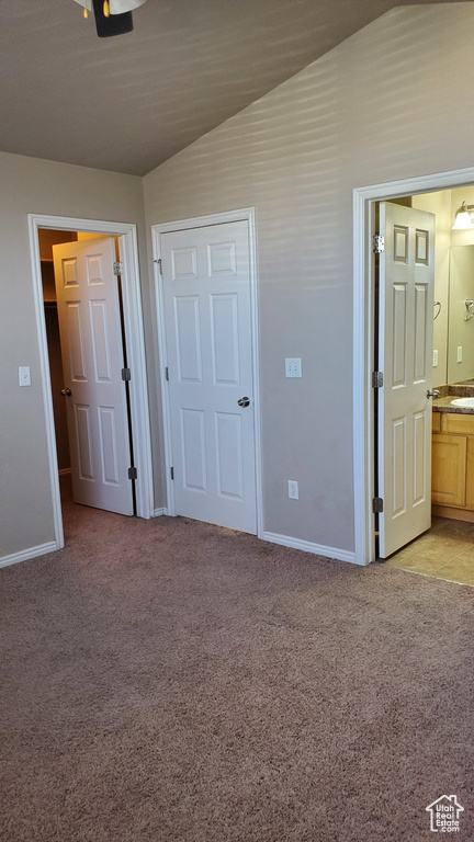 Unfurnished bedroom with light colored carpet, vaulted ceiling, and ensuite bathroom