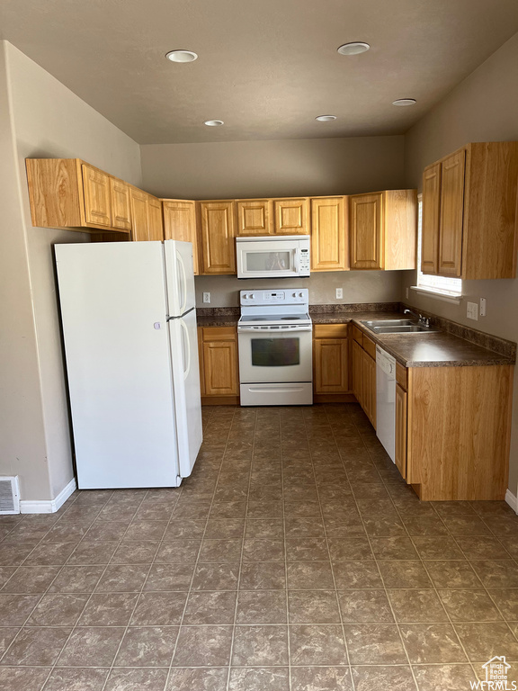 Kitchen with sink, dark tile patterned flooring, and white appliances