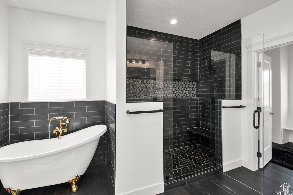 Bathroom featuring independent shower and bath, tile patterned flooring, and tile walls