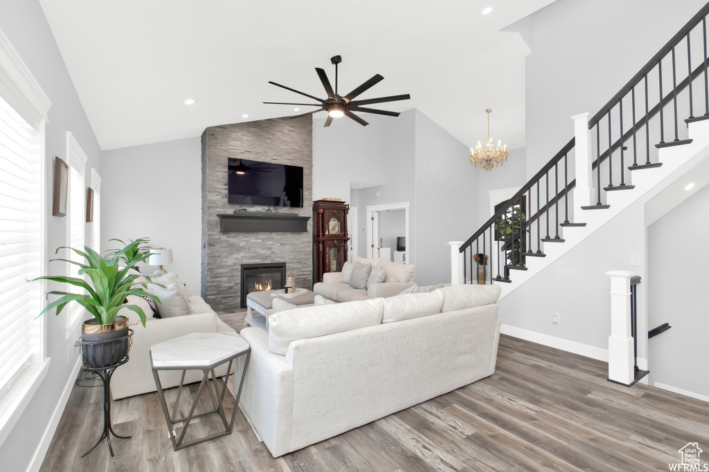 Living room with a fireplace, ceiling fan with notable chandelier, hardwood / wood-style flooring, and a healthy amount of sunlight