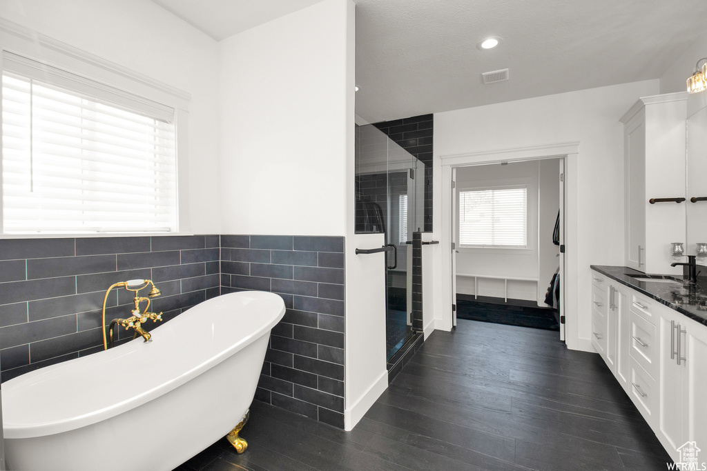 Bathroom featuring vanity, shower with separate bathtub, hardwood / wood-style floors, and tile walls