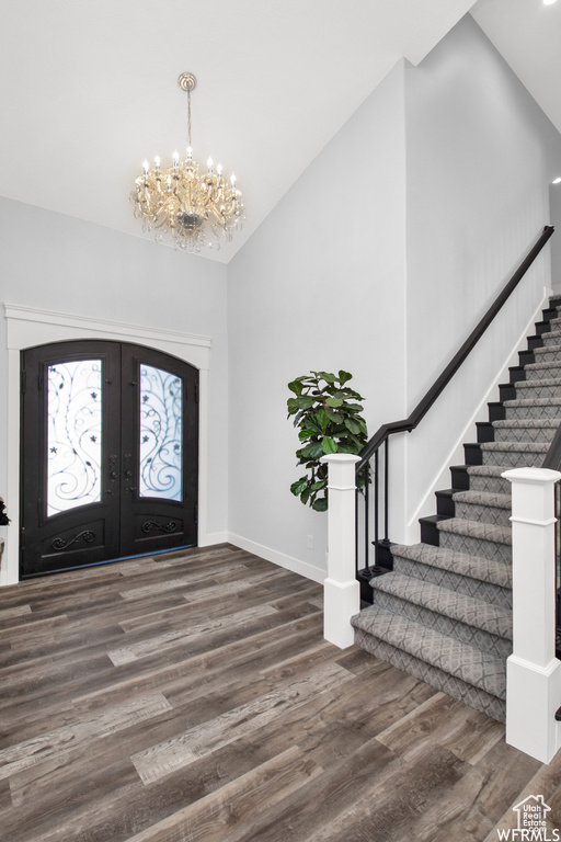 Foyer entrance featuring hardwood / wood-style flooring, french doors, a chandelier, and a high ceiling