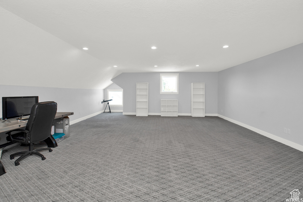 Carpeted office space with lofted ceiling