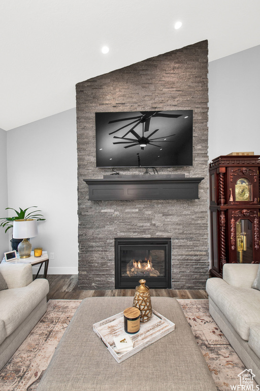 Living room featuring lofted ceiling, a stone fireplace, and dark hardwood / wood-style floors