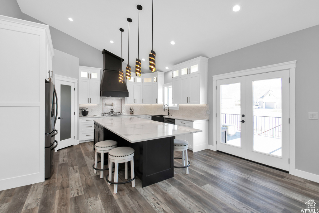 Kitchen with custom exhaust hood, lofted ceiling, decorative backsplash, and dark hardwood / wood-style floors