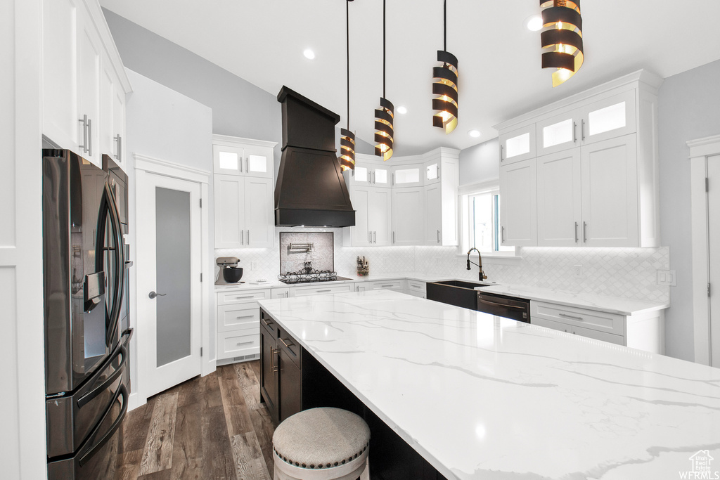 Kitchen featuring backsplash, premium range hood, pendant lighting, and black appliances