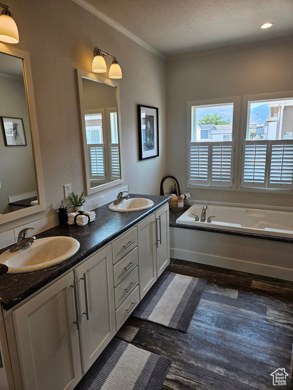 Bathroom with hardwood / wood-style floors, double sink vanity, a bath, and crown molding