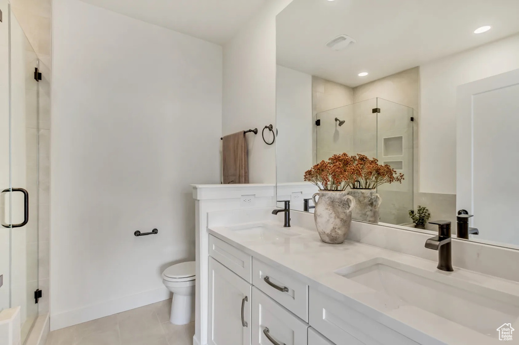 Bathroom with a shower with door, tile patterned flooring, toilet, and double sink vanity