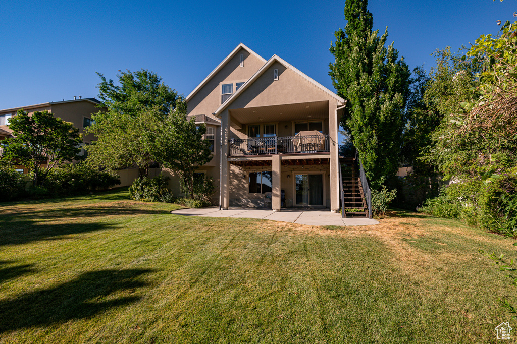 Rear view of house featuring a deck, a patio, and a yard