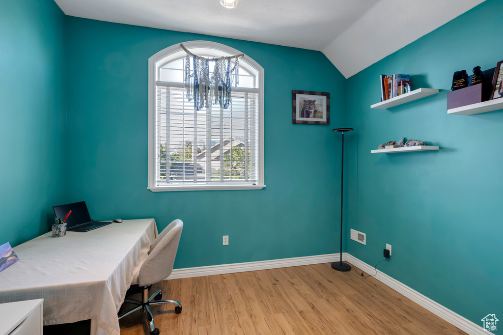 Home office featuring vaulted ceiling, light hardwood / wood-style flooring, and a notable chandelier