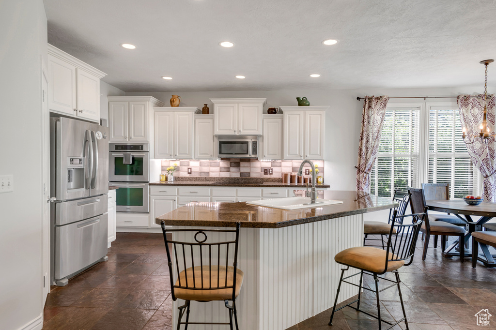 Kitchen featuring sink, white cabinetry, stainless steel appliances, and backsplash