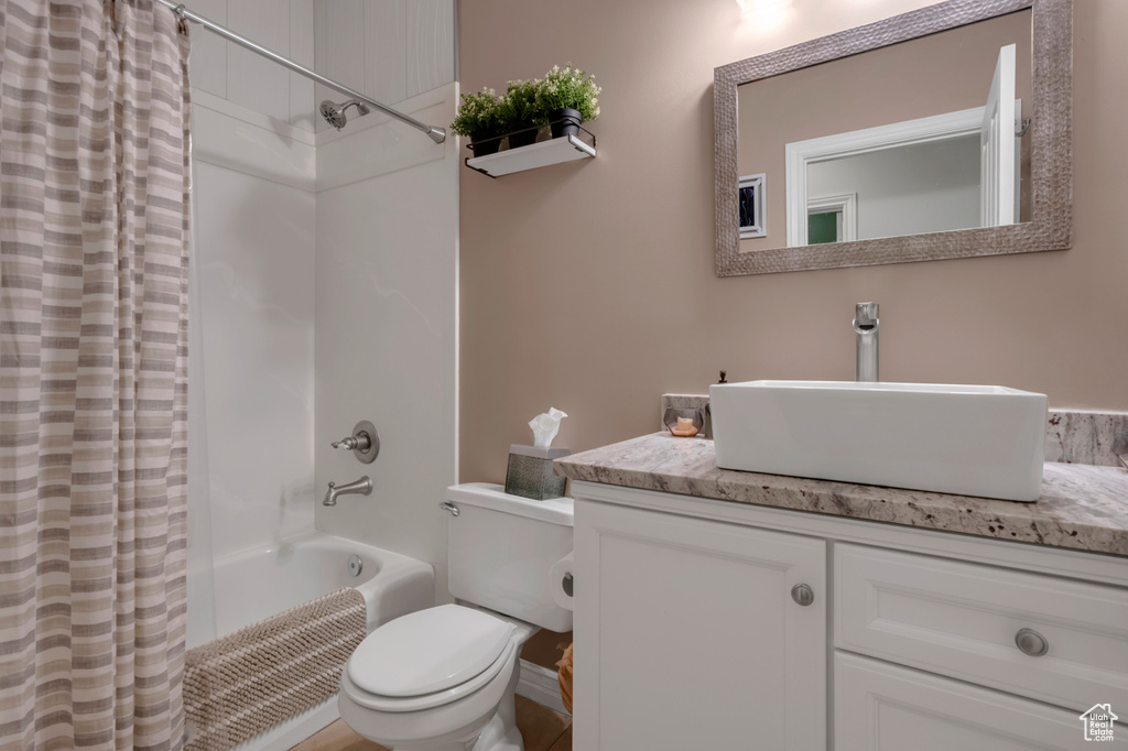 Full bathroom with shower / bath combo with shower curtain, vanity, and toilet