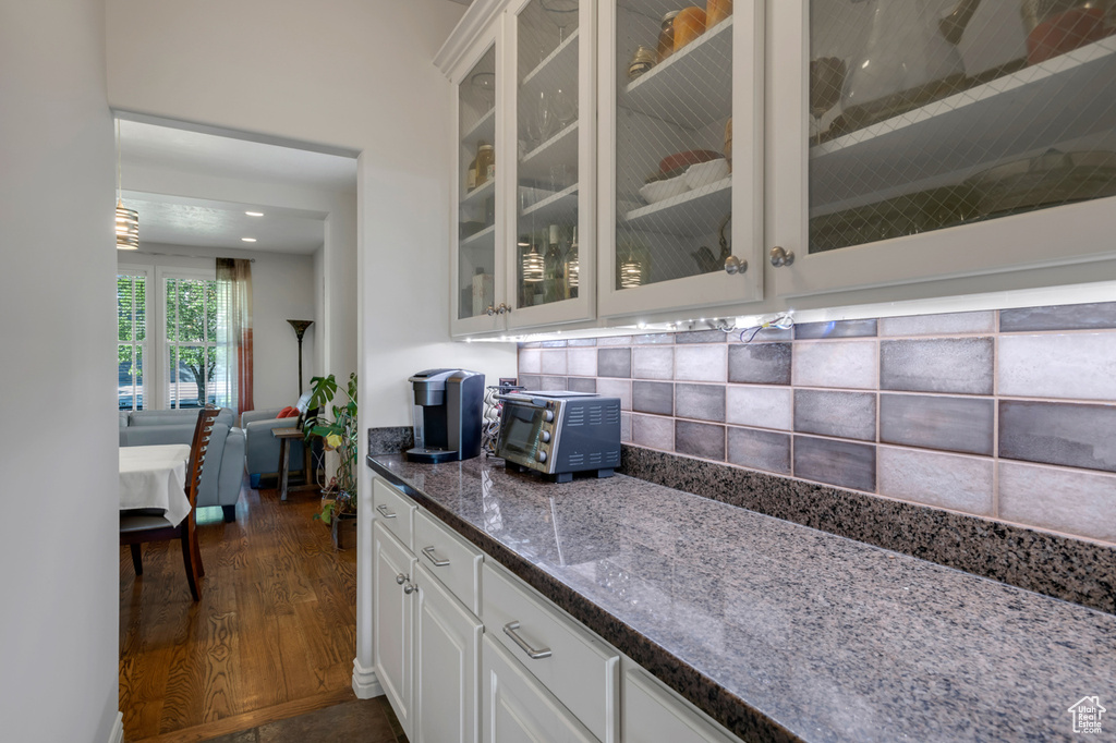 Kitchen featuring white cabinetry, dark stone countertops, decorative backsplash, and dark wood-type flooring