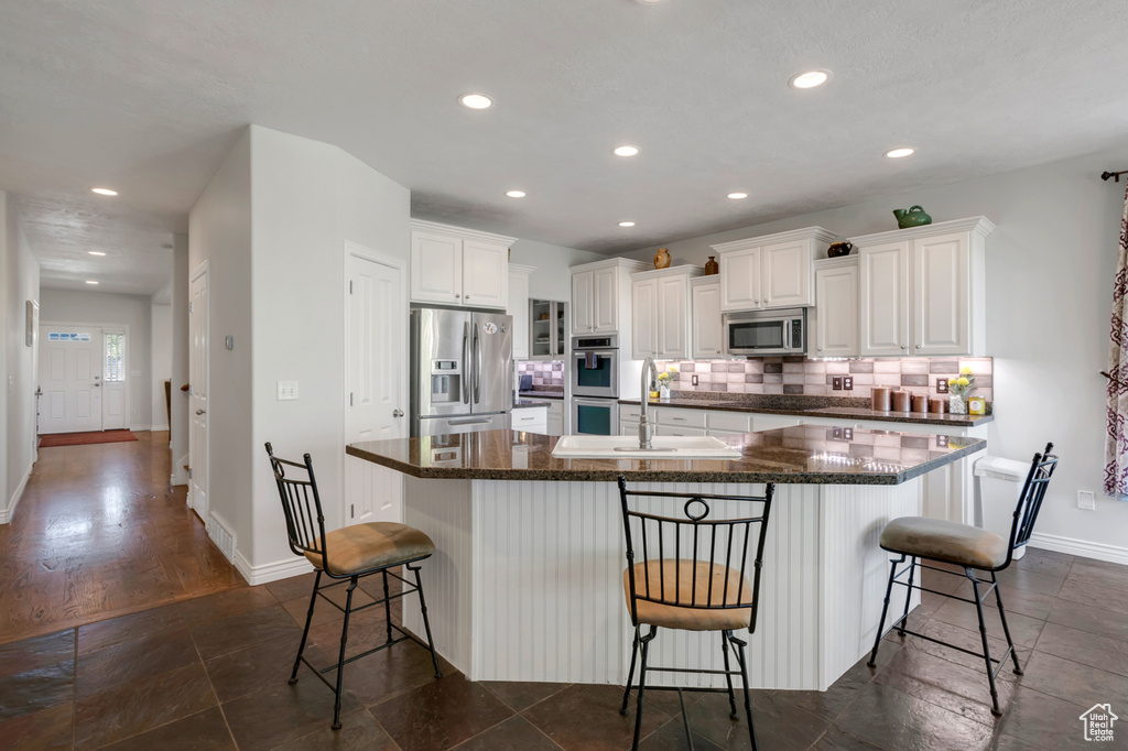 Kitchen featuring appliances with stainless steel finishes, decorative backsplash, dark hardwood / wood-style floors, a kitchen breakfast bar, and a spacious island