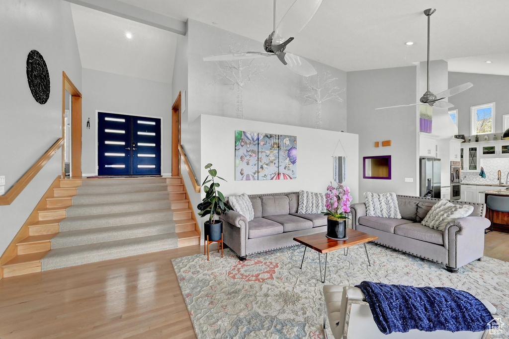 Living room featuring high vaulted ceiling, light hardwood / wood-style flooring, and ceiling fan