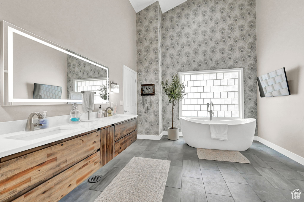 Bathroom featuring dual vanity, tile patterned floors, high vaulted ceiling, and a bath