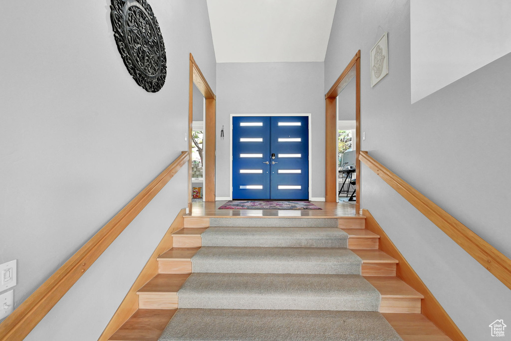 Stairway featuring hardwood / wood-style flooring, a towering ceiling, and french doors