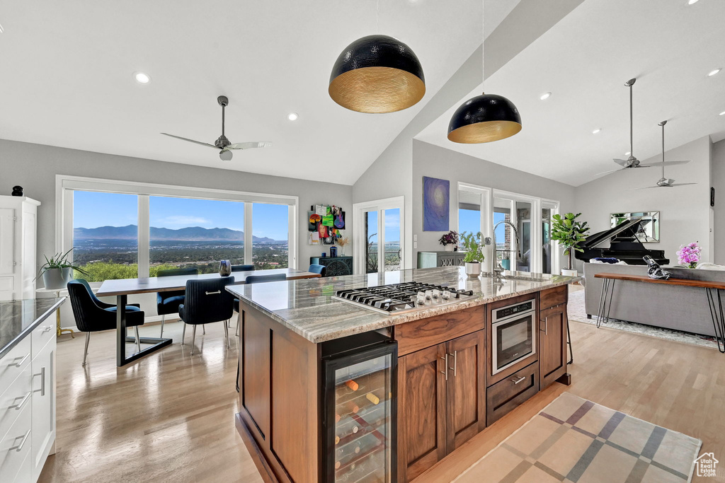 Kitchen with ceiling fan, a mountain view, wine cooler, stainless steel gas cooktop, and light hardwood / wood-style flooring