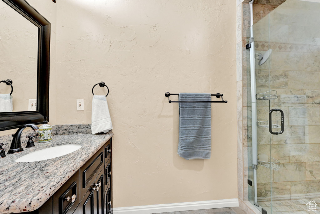 Bathroom featuring a shower with door and vanity