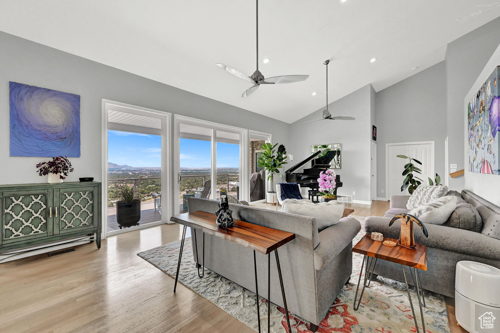 Living room featuring high vaulted ceiling, light wood-type flooring, and ceiling fan