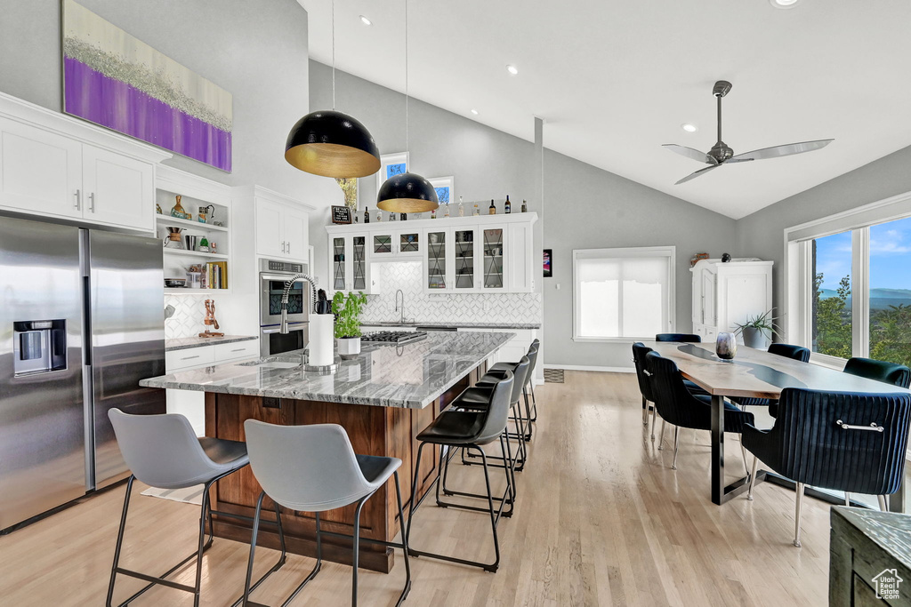 Kitchen with high vaulted ceiling, tasteful backsplash, light stone counters, and stainless steel appliances